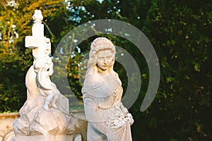 Sculpture of a woman at old cemetery. Close Up of stone figure and cross monument at cemetery. Old stone Graveyard statue on funer