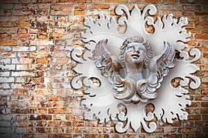 Sculpture of a wooden angel against an old classical plaster frame