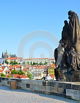 Sculptures on famous Charles Bridge in Prague, Czech Republic with blue sky. Prague Castle and other historical buildings in