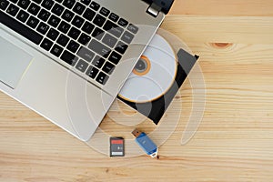 SD Card, Flash Drive USB3.0 and CD DVD Drive Writer Burner Reader of laptop computer on wooden background