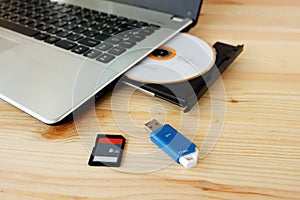 SD Card, Flash Drive USB3.0 and CD DVD Drive Writer Burner Reader of laptop computer on wooden background
