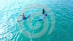 Sea, adventure and people on paddle board from drone with blue water, freedom and tropical holiday. Fun, sports and