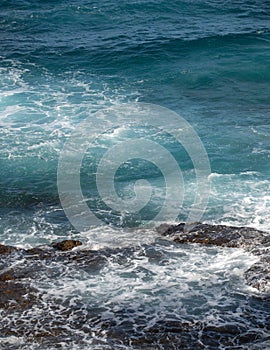 Sea background. Ocean wave crashing on rock coast with spray and foam before storm.