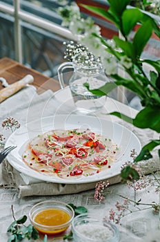 Sea bass carpaccio with baked strawberries and citrus dressing. Dish in the restaurant, strawberry menu. Summer light dish for