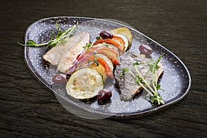 Sea bass fillet with vegetables ratatouille . On dark background, isolated