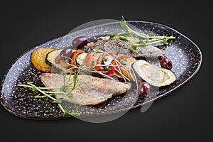 Sea bass fillet with vegetables ratatouille . On dark background, isolated