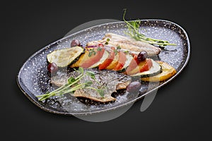 Sea bass fillet with vegetables ratatouille . On dark background, isolated