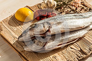 Sea bass fish with garlic, rosemary, tomatos and lemon on a wood table from above