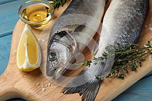 Sea bass fish and ingredients on light blue wooden table, closeup