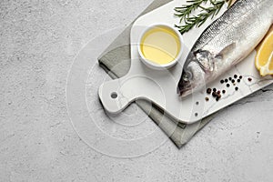 Sea bass fish and ingredients on light grey table, above view. Space for text