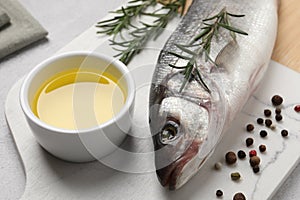 Sea bass fish and ingredients on light grey table, closeup