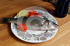 Sea bass, spigola. Fresh fish with the head on plate.