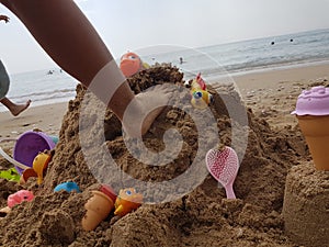 Sea beach castle of sand made by children with toys on it by t