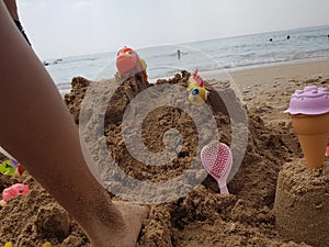 Sea beach castle of sand made by children with toys on it by t