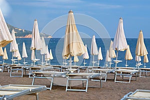 Sea beach with many sun umbrellas and chairs waiting for tourists. Happy summer vacations concept. Sunny summer beach