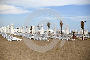 The sea beach of the resort hotel. Empty sun loungers, umbrellas from the sun on the sand, palm trees.