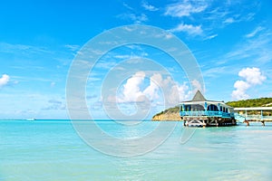 Sea beach with wooden shelter on sunny day in antigua. Pier in turquoise water on blue sky background. Summer vacation on caribbea