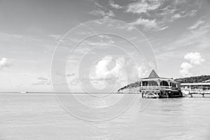 Sea beach with wooden shelter on sunny day in antigua. Pier in turquoise water on blue sky background. Summer vacation