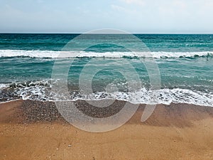 Sea blue aquamarine waves line sunny sand beach. Soft wave of ocean foam.