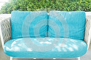 Sea-blue sofa rattan chairs set outside against at sidewalk swimming pool