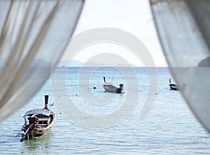 Sea, boats from hotel room window, white curtain