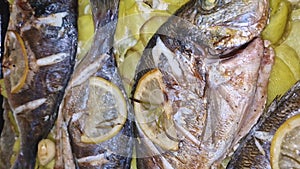 Sea Bream fish baked in a tray among potatoes with garlic lemon and rosemary