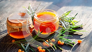 Sea buckthorn jam in glass jars, branch and berries