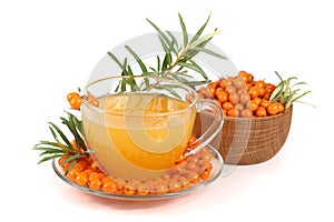 Sea buckthorn tea in a glass and wooden bowl with berries isolated on white background