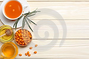 Sea buckthorn in wooden bowl, honey, Sea buckthorn juice on wooden table. top view with copy space