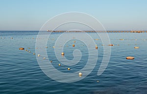 Sea buoys  on the sea water on the background of a long old pier at sunset