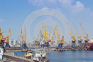 Sea cargo port with harbor cranes, sea tugs on foreground
