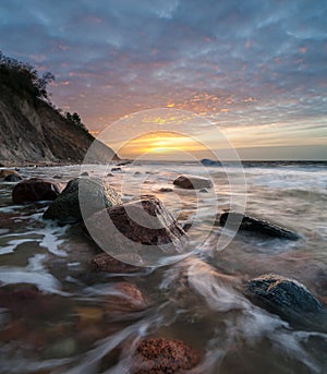 Sea cliff and beach lit by the setting sun