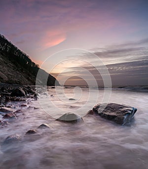 Sea cliff and beach lit by the setting sun