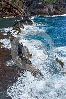 Sea coast with rocky cliffs. Blue water and big stones on the seashore. Rocks on the coast, summer background.