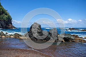 Sea coast with rocky cliffs. Blue water and big stones on the seashore. Rocks on the coast, summer background.