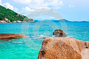 Sea coast with a rocky shore and a mountain covered with greenery. Vacation in Thailand on a tropical island