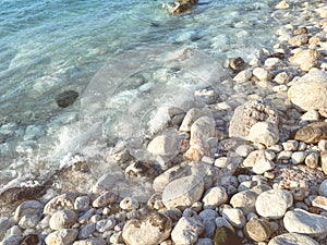 Sea coast. stones in the water. small and large stones lie among the water on the coast. a white sea wave comes to the stones,