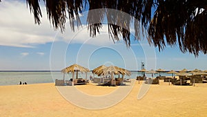 Sea coast with thatched umbrellas on a sandy beach. Seascape on the beach at the end of the holiday season. A great place to relax