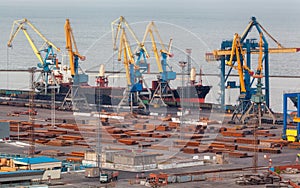 Sea commercial port at night in Mariupol, Ukraine. Industrial view. Cargo freight ship with working cranes bridge in sea port