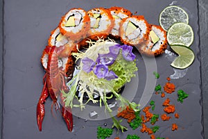 Sea crawfish and sushi on a slate dark plate with liquid smoke