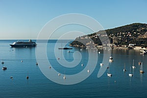 Sea with cruise ship and luxury boats with small village near