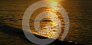 Sea evening sunlight reflecting surface is golden.
