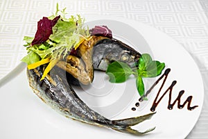 Sea fish, dressed with vegetables and olives on a white plate. Sea fish, dressed with vegetables and olives on a white plate. Hori