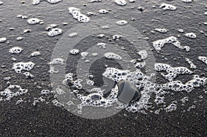 Sea foam on black sand