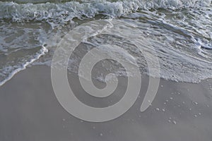 Sea foam melts on the white sand of the beach