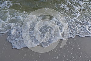 Sea foam melts on the white sand of the beach