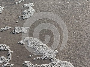 Sea foam pattern in the water over sand