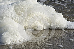 Sea foam on a sand tropical beach. Travel and tourism, bubbles and macro waves