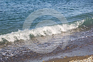 The sea foamy waves on an empty pebble beach