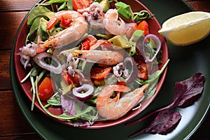 Sea food salad with shrimps, avocado, cherry tomatoes, red hot chilly pepper, red onion, arugula, beet leaves,